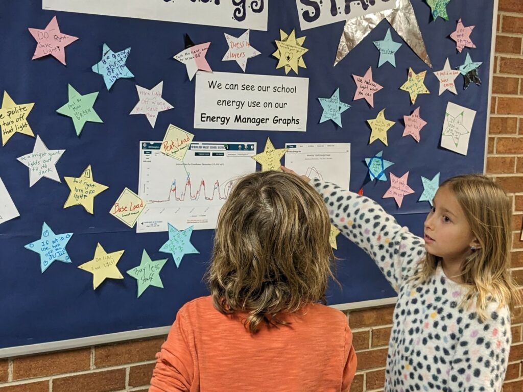 Children at Eisenhower Elementary School, discussing their eGuage Demonstration at a bulletin board. Students took turn standing at the bulletin board and explaining how the eGuage improves their school's energy efficiency. 